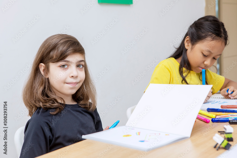 Caucasian kid smiling to camera while drawing blue