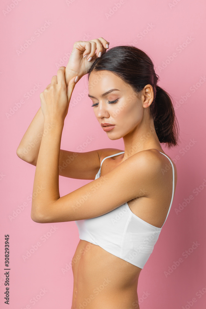 side view on attractive female brunette with tail hair, wearing white underwear. healthy life concept, isolated over pink background