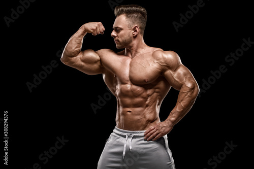Muscular man showing muscles isolated on the black background. Strong male naked torso abs