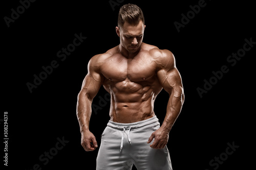 Muscular man showing muscles isolated on the black background. Strong male naked torso abs