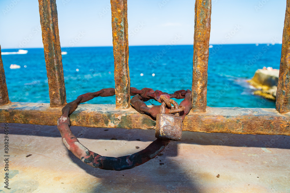 Fototapeta premium Chain and padlock on railings in front of the sea.