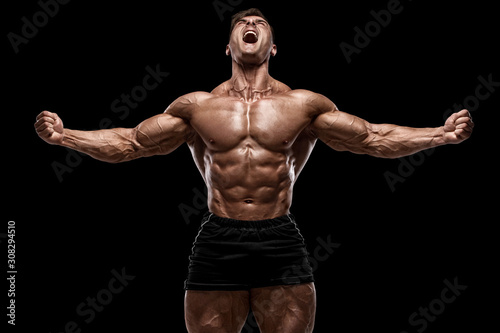 Muscular man showing muscles isolated on the black background. Strong male na...