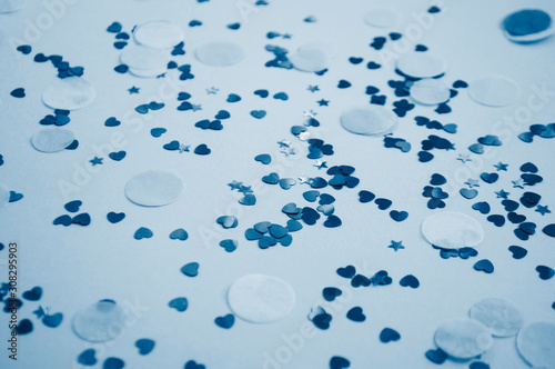 Defocused and blurred beautiful heart and stars shaped confetti on blue background. 2020 color trend.