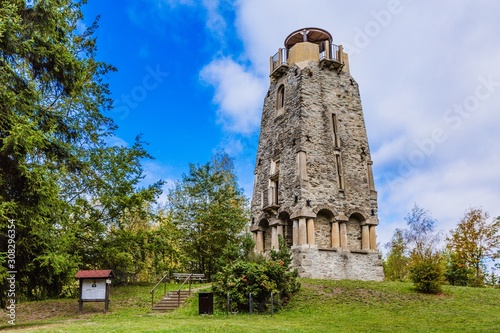 Zelena hora, Pelhrimov / Czech Republic - September 13 2019: Bismarck tower made of stone built in 19th century close to Cheb surrounded with green trees. Sunny day with blue sky and clouds. photo