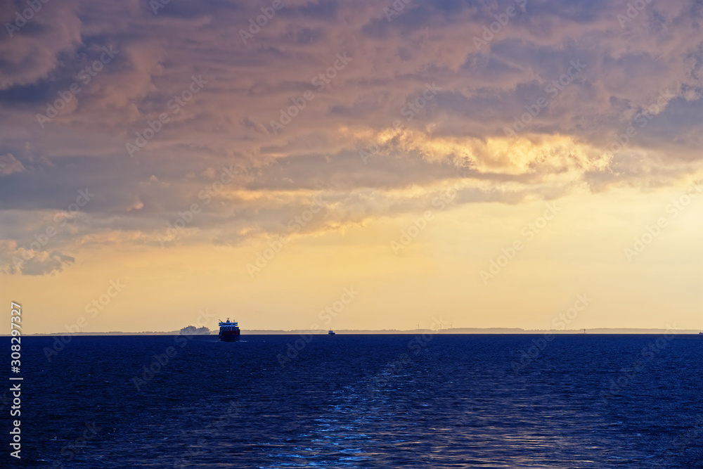 Colorful cloudy sky above sea and wake from cruise ship at sunset