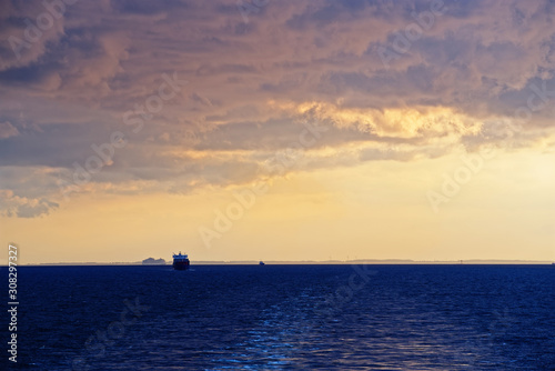 Colorful cloudy sky above sea and wake from cruise ship at sunset