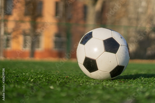 A black and white soccer ball on an artificial turf on a clear sunny day. © Виктор Кеталь