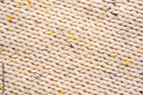 Texture of Wool Knit Beige Fabric Interspersed with Yellow Yarn. Sweater Background Close-Up View