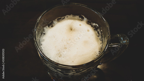 Light, fresh and tasty beer with a white fluffy foam on a dark background. Beer Day Celebration. Alcoholism concept. Photo capture