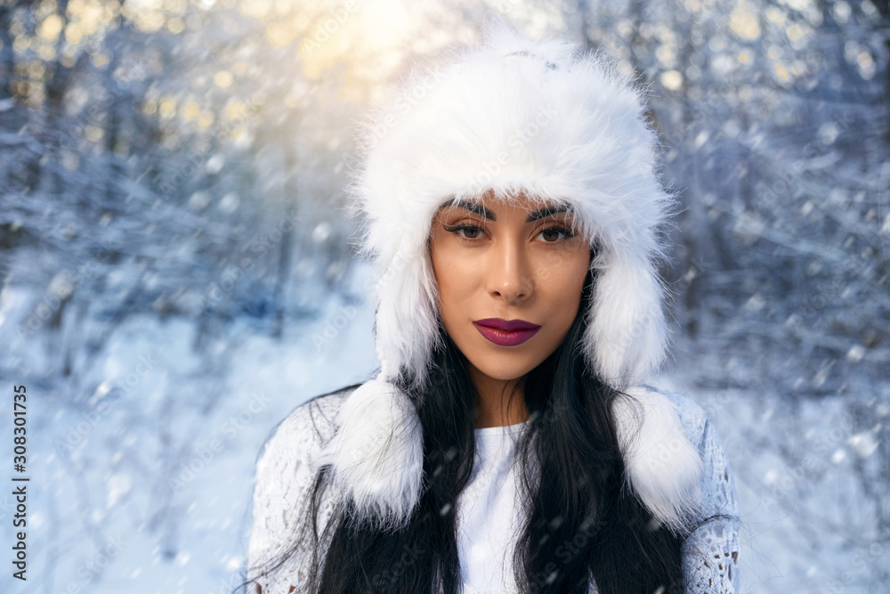 Girl in white stylish hat in winter forest.
