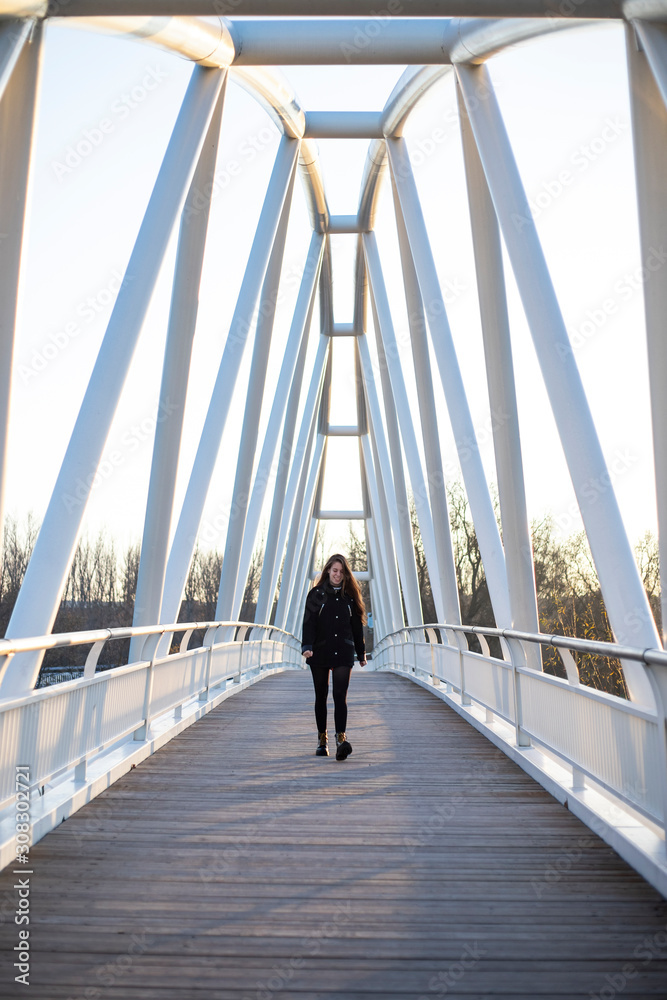 young woman walking coming back with a big smile alone in a bridge young woman walking coming back with a big smile alone in a bridge