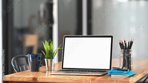 Laptop computer on workspace table in office room.