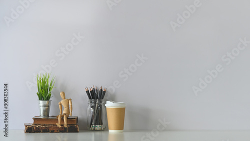 Decorative workspace with books, dummy model, coffee, pencil and house plant on white table. photo