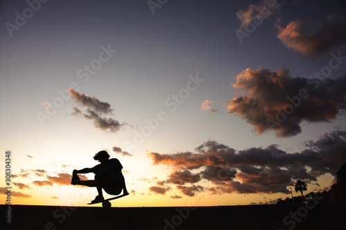 Silhouette of the man standing on balance board on one leg on the bending knee © fesenko