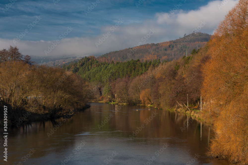 Ohre river in Perstejn village with blue sky and color forests and mountains