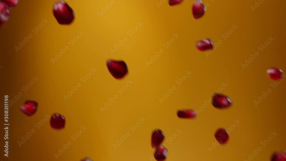 Juicy grains of ripe pomegranate are falling on the yellow background Juicy grains of ripe pomegranate are falling on the yellow background