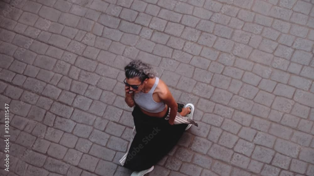 aerial view of short-haired woman walking on steep road aerial view of short-haired woman walking on steep road