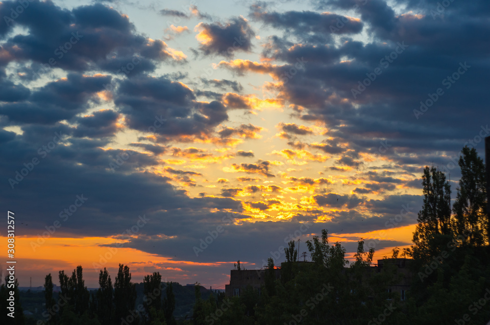 Landscape with dramatic light - beautiful golden sunset with saturated sky and clouds.