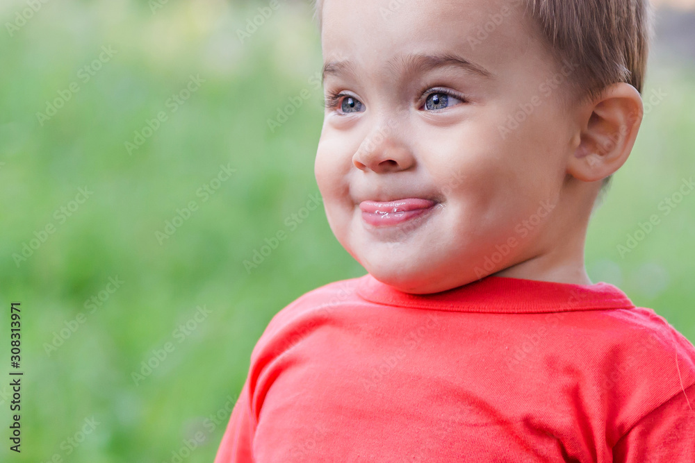 funny child shows language, makes a face, cute funny kid in the Park. portrait of a happy smiling child funny child shows language, makes a face, cute funny kid in the Park. portrait of a happy smiling child