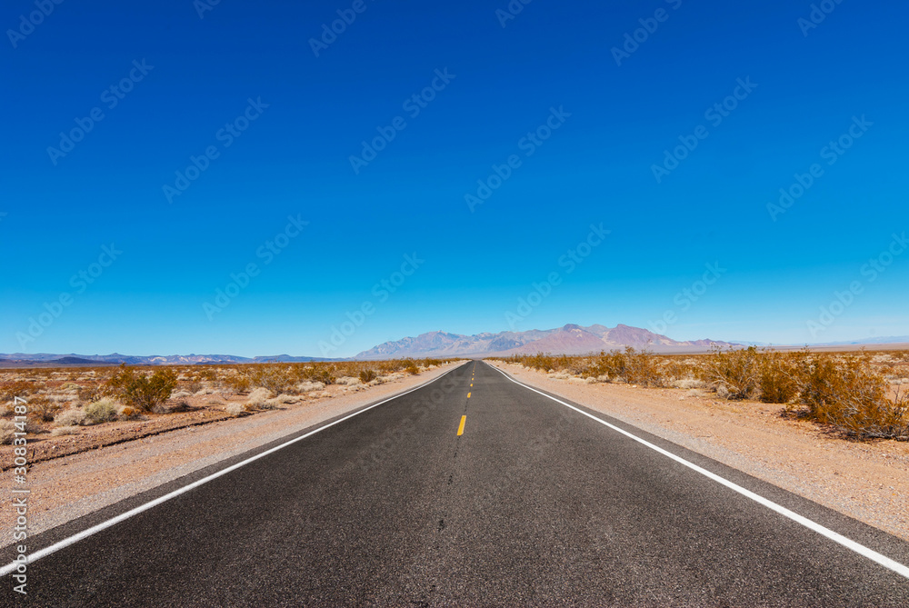 The road passing through the desert against the backdrop of mountains.