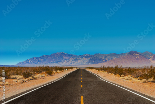 The road passing through the desert against the backdrop of mountains.