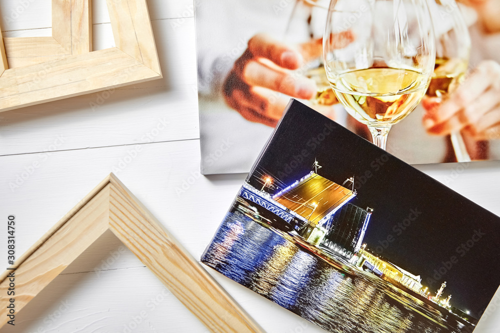 Canvas prints on white wooden table.  Photo industry. Colorful photographs stretched on stretcher bars. Photos printed on glossy synthetic canvas with gallery wrapping