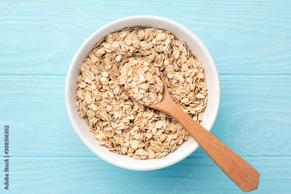 Rolled oats, oat flakes in bowl on blue background Rolled oats, oat flakes in bowl on blue background