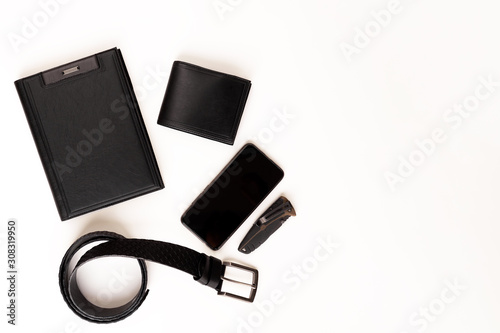 Men's set. Black leather diary, black leather belt, black leather wallet, smart watch, smartphone and knife on a white background. View from above.