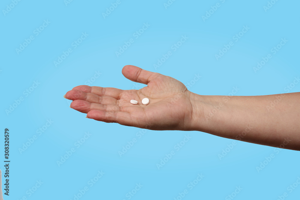 woman holds out her hand with two white pills on a blue background, concept of health insurance, health care, assistance, isolate, copy space