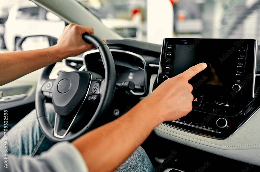 Naklejka premium Cropped image hand of man using navigation system or dashboard while driving a car.