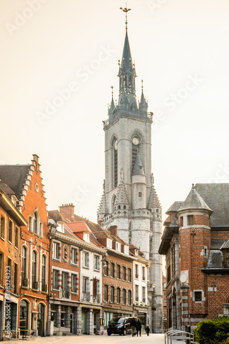Tall medieval bell tower rising over the street with old european houses  Tournai  Walloon municipality  Belgium