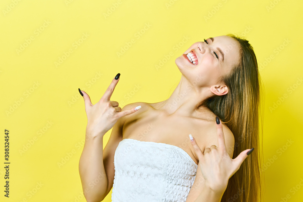 Obraz premium Young crazy lady. Music lover rock fan concept. Close up photo portrait of excited funky funny comic cheerful lady making stick tongue out sign isolated on a yellow background