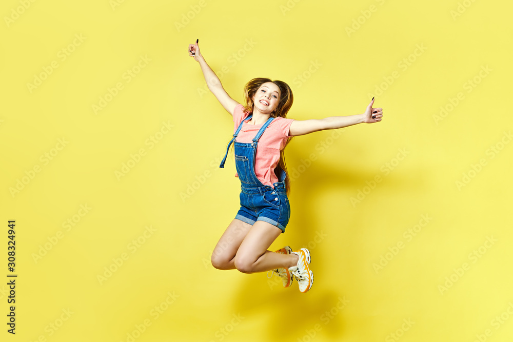 Girlish, funky, happiness, dream, fun, joy, summer concept. Very excited happy cute girl is jumping up, in summer outfit, on yellow background Girlish, funky, happiness, dream, fun, joy, summer concept. Very excited happy cute girl is jumping up, in summer outfit, on yellow background