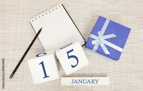 Calendar with trendy blue text and numbers for January 15 and a gift in a box.