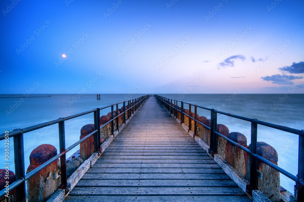 Long wooden pier extends over water toward the horizon. A leading line to the horizone