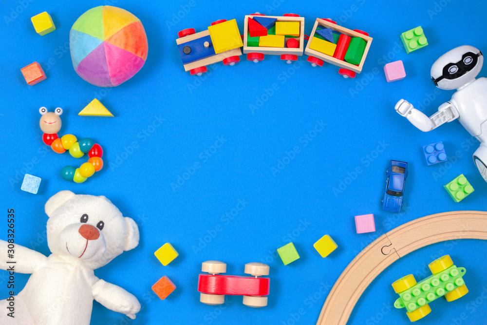 Kids toys background. White teddy bear, wooden train, toy car, robot, colorful blocks on blue background