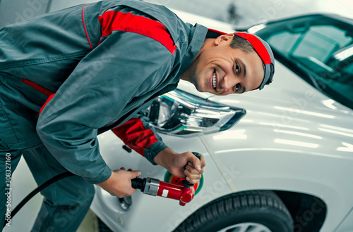 Auto mechanic buffing car autobody. Car repair and maintenance. photo