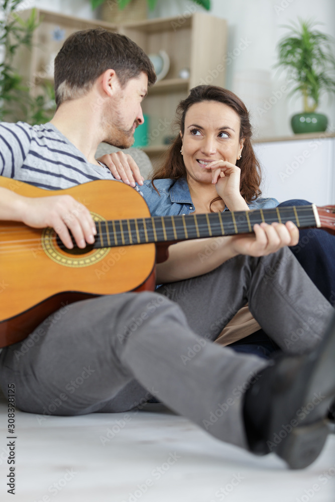 Fototapeta premium couple relaxing in the home man playing guitar