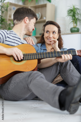 couple relaxing in the home man playing guitar