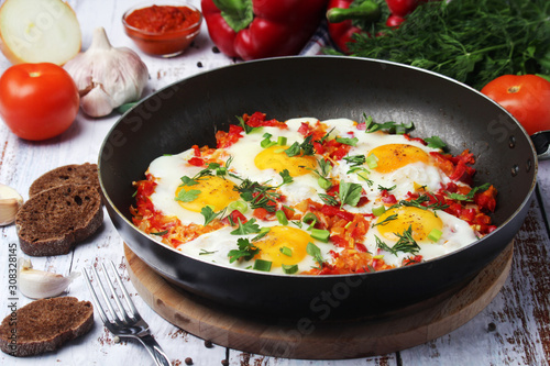 Shakshouka with five cooked eggs on top of tomato sauce in cast iron skillet 