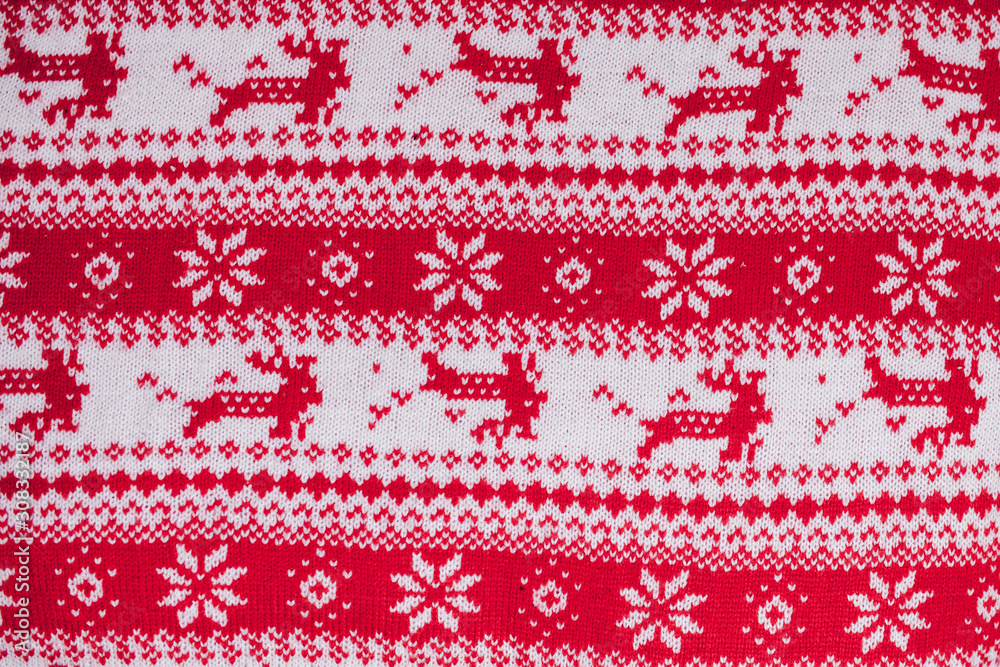 Real red knitted background with white Christmas deer and snowflakes Real red knitted background with white Christmas deer and snowflakes