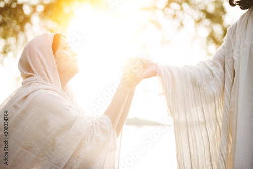 Foto Female wearing a biblical robe and grabbing the hand of Jesus Christ for help an