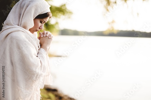Obraz na plátne Shallow focus shot of a female wearing s biblical gown and praying while her eye
