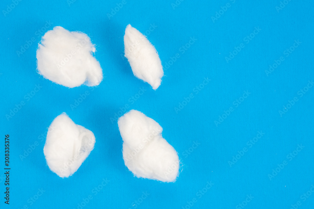 small rolls of medical cotton on blue background close-up small rolls of medical cotton on blue background close-up