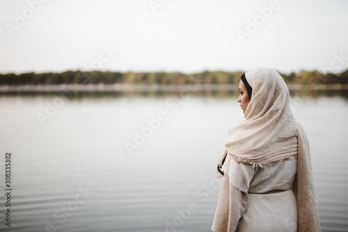 Shallow focus shot from behind of a female wearing a biblical gown while looking in the distance