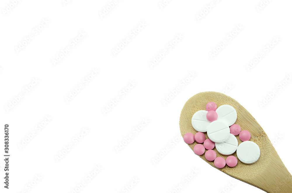 multi-colored tablets in a wooden spoon on a white background isolated, blank, mock up, copy space multi-colored tablets in a wooden spoon on a white background isolated, blank, mock up, copy space