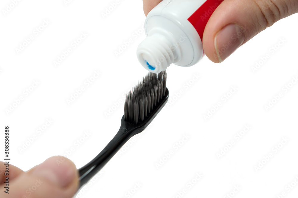 a toothbrush and tube of toothpaste in a hand isolated on white background, squeezing toothpaste on the toothbrush a toothbrush and tube of toothpaste in a hand isolated on white background, squeezing toothpaste on the toothbrush