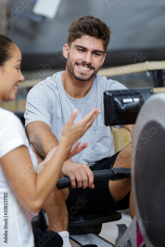 female trainer assisting a man on rowing machine at gym