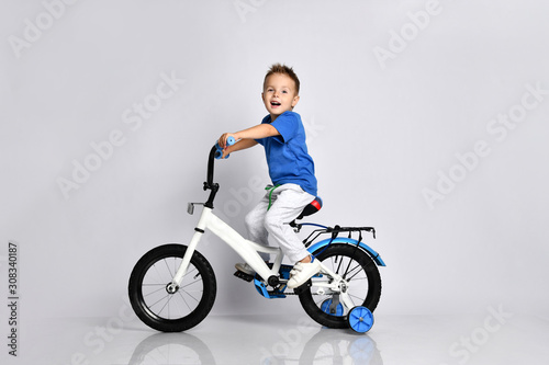 young boy happily riding on a bicycle on isolated background