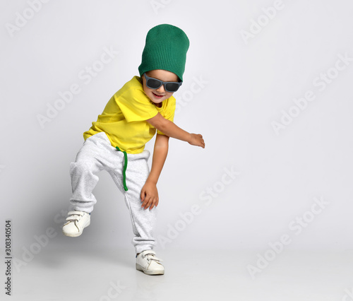 cheerful kid hipster boy in a green hat dancing in wide pants © FAB.1